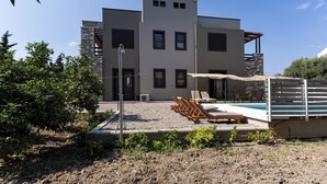 A modern building with a pool, outdoor seating, and a garden area. - Villa Astravi with Private Pool (Ιαλυσός)