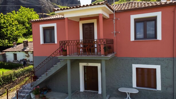 Une maison à deux étages avec un balcon, un escalier et une petite table.