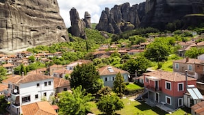 Un quartier résidentiel où les maisons se distinguent par leurs toits recouverts de tuiles rouges, le tout étant entouré d’une végétation luxuriante et de falaises rocheuses.