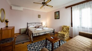 Une chambre à coucher comprenant un lit, une chaise, un canapé, une petite table et un ventilateur de plafond.