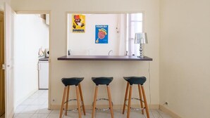 Een keuken met een bargedeelte, drie krukken en twee posters aan de muur.