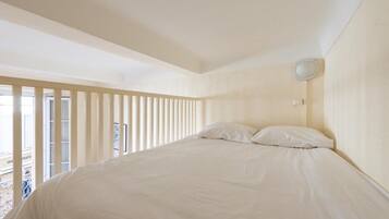 A bedroom with a large bed, a window with blinds, and a ceiling light.