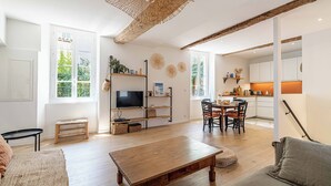 Un salón amplio con una mesa de centro de madera, un televisor y una zona de comedor con sillas y una mesa.