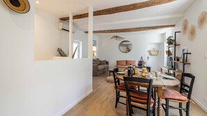 Un comedor con una mesa y sillas de madera, un espejo y una lámpara colgante.