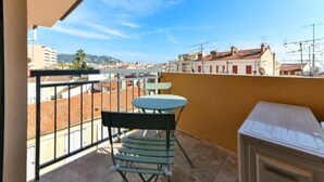 Un balcon avec une table et des chaises, un lave-linge et une vue sur le paysage urbain.