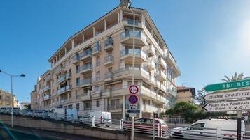 Un edificio de varios pisos con balcones, un letrero de 'prohibido estacionar' y señales que indican la dirección a atracciones locales.