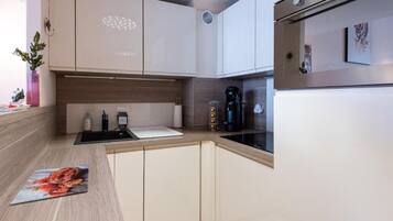 Una cucina moderna con pensili bianchi, un piano di lavoro nero e un forno in acciaio inossidabile.