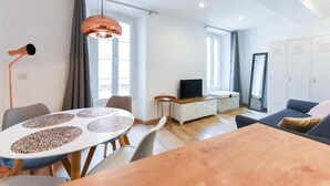 Ett modernt vardagsrum med ett runt matbord, en soffa, en tv och en garderob.