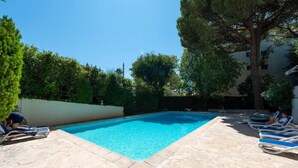 A rectangular swimming pool with clear blue water, surrounded by a stone deck.