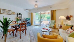 A spacious living area with a dining table, comfortable seating, a television, and a large sliding glass door leading to an outdoor area.