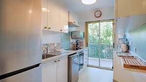 A modern kitchen with white cabinets, a stainless steel oven, and a large window.