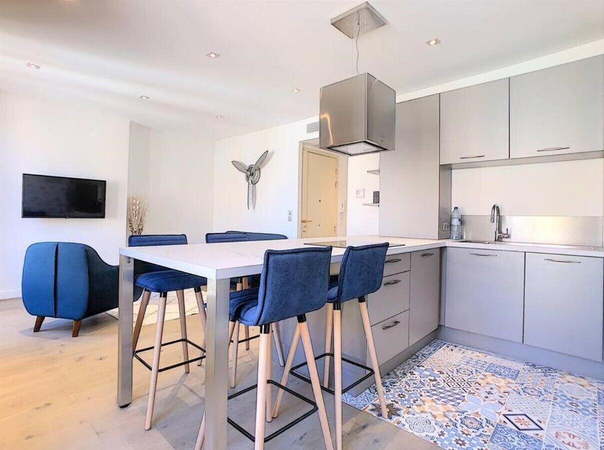 Una cucina moderna con zona pranzo, caratterizzata da un tavolo bianco, sedie blu e un pavimento decorato.
