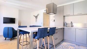 Una cucina moderna con zona pranzo, caratterizzata da un tavolo bianco, sedie blu e un pavimento decorato.