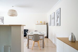 A modern dining area with a table set for four, a hanging pendant light, and framed artwork on the wall. - Le Corail spacieux avec beau et ample balcon (Cannes)