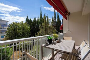 A balcony with a table and chairs, potted plants, and a railing.