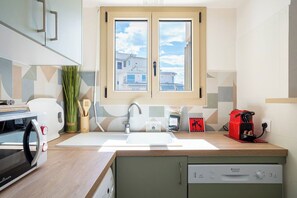 A compact kitchen with a window, a microwave, a toaster, a sink, and a dishwasher. - Le Corail spacieux avec beau et ample balcon (Cannes)