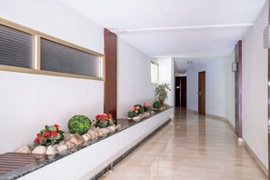 A hallway with a marble bench, potted plants, and a wooden door at the end. - Le Corail spacieux avec beau et ample balcon (Cannes)