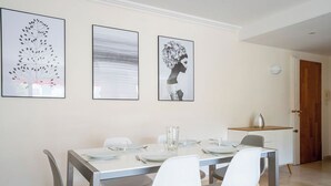 Un comedor con una mesa rectangular, cuatro sillas y tres cuadros en la pared.