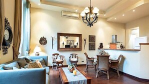 A living room with a sofa, dining table, chairs, and a chandelier.