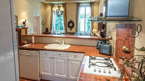 A kitchen with white cabinets, a gas stove, a sink, and a window with curtains.