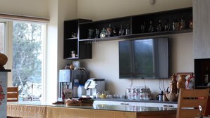 Cozinha com uma janela grande, micro-ondas embutido e prateleira com diversos utensílios de cozinha.