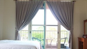 Quarto com uma cama grande, varanda com cadeiras e cómoda de madeira.