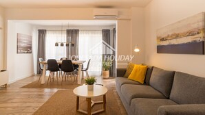 A modern living room with a sofa, a dining table with chairs, and a coffee table.