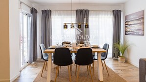 A dining area with a wooden table, black chairs, and a hanging light fixture.