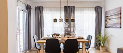Un comedor con mesa de madera, sillas negras y una lámpara colgante.