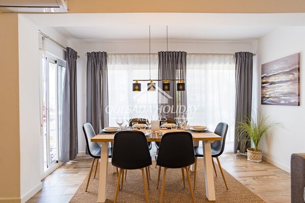 A dining area with a wooden table, black chairs, and a hanging light fixture.