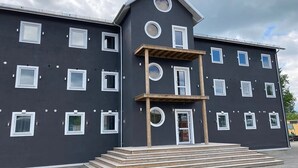 Un edificio de varios pisos con fachada simétrica, destacando una entrada central con escalones, múltiples ventanas y techo plano.