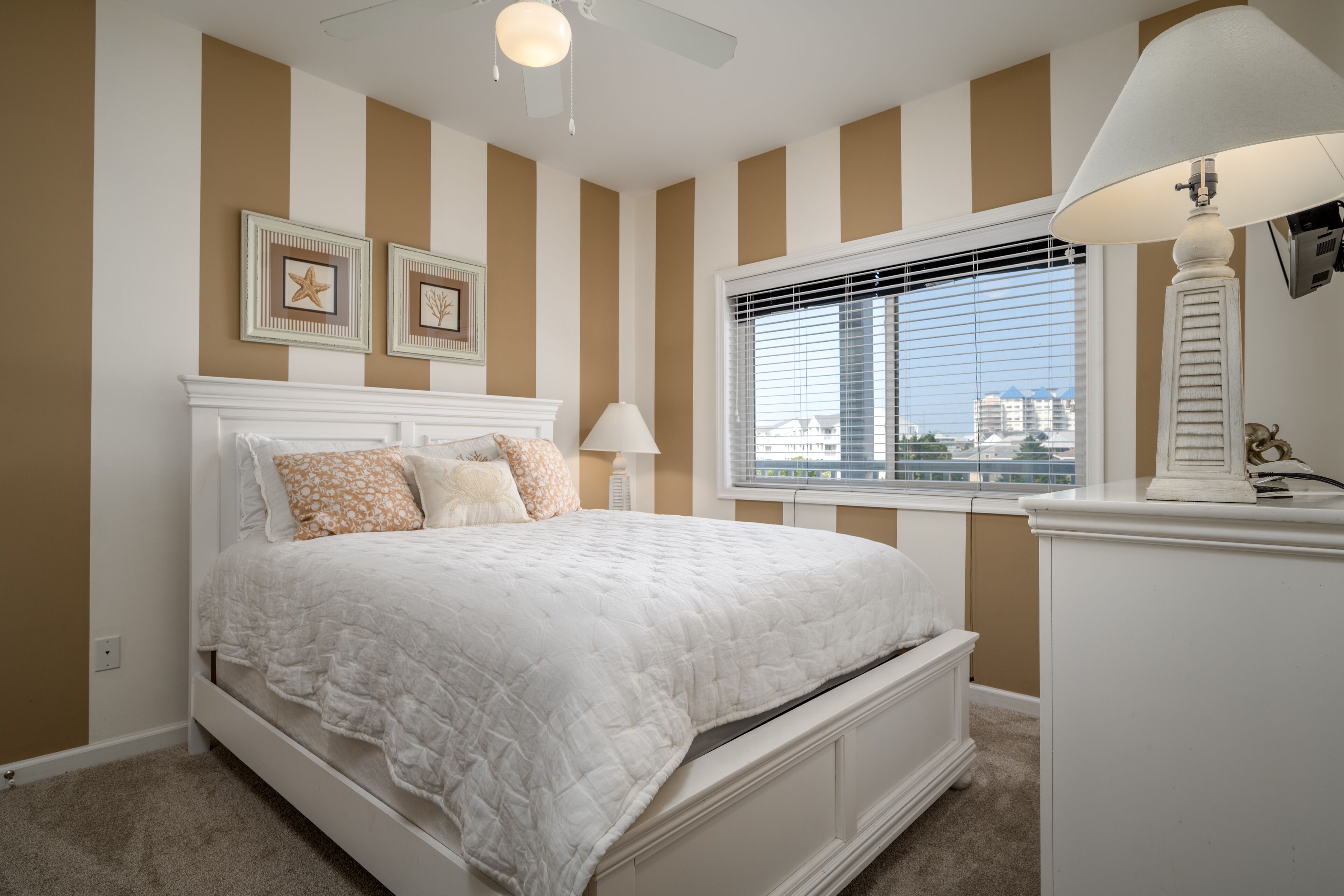 A bedroom with a large bed, a window with blinds, and a ceiling fan.
