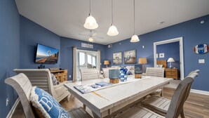 Ein Essbereich mit weißem Tisch und Stühlen, blauen Wänden und einem Deckenventilator.