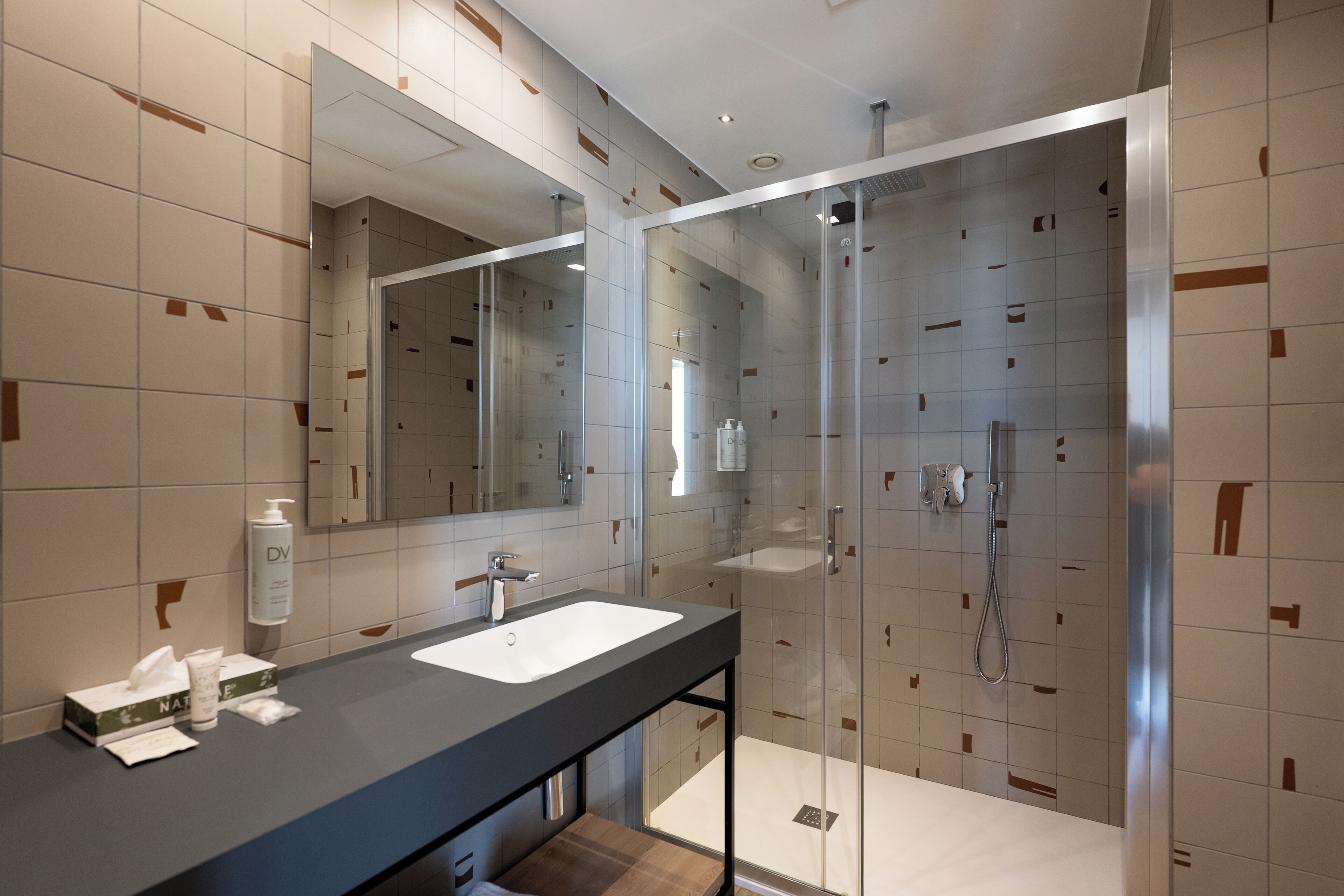A modern bathroom with a glass-enclosed shower, a large mirror, and a vanity with a sink.