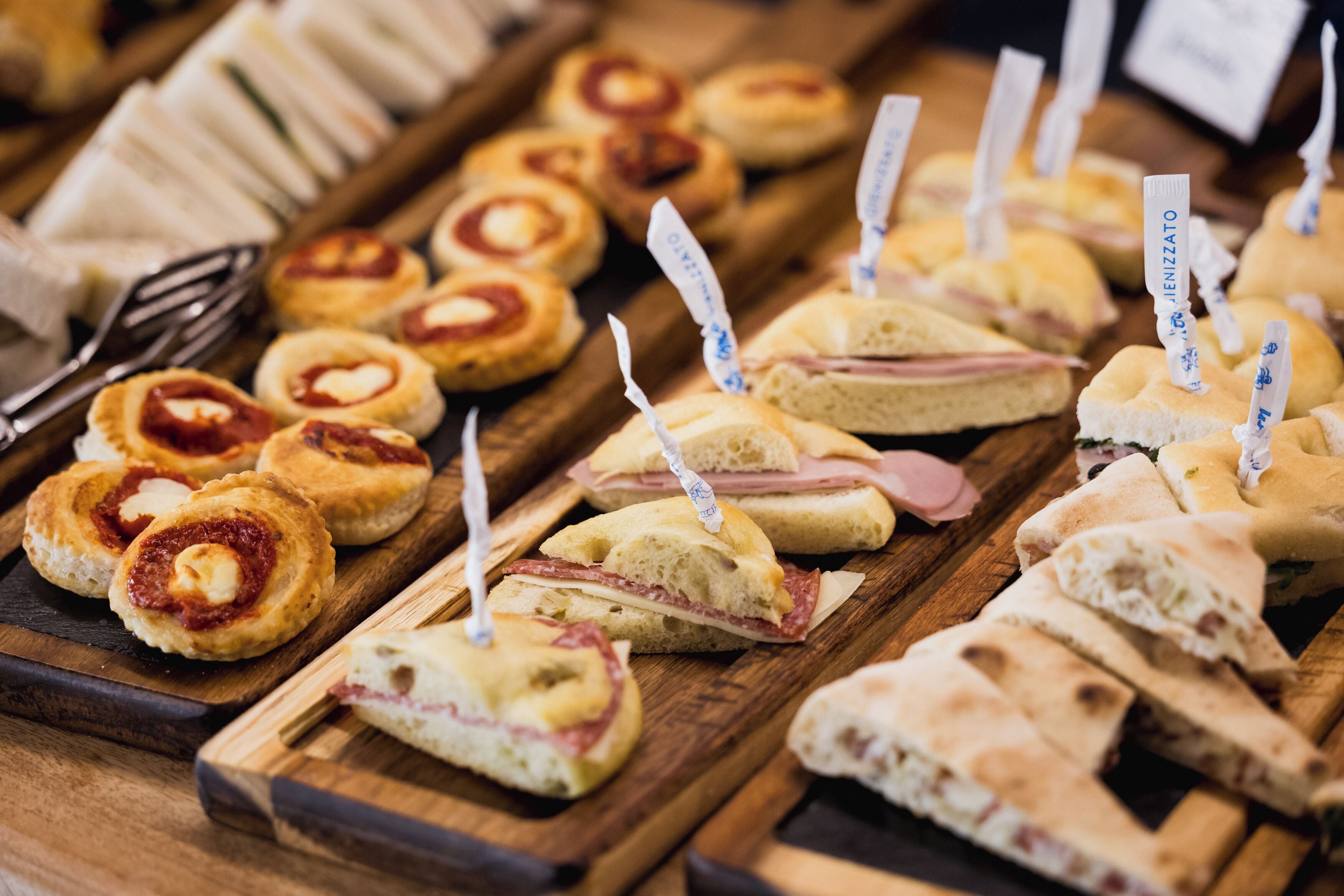 A variety of sandwiches and pastries on wooden boards.