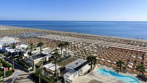 A resort with a large pool, beach umbrellas, and a view of the ocean. - Hotel Sporting (Riccione)
