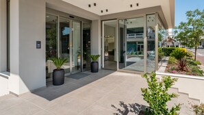 A modern building with large glass doors, potted plants, and a well-maintained outdoor area. - Hotel Sporting (Riccione)
