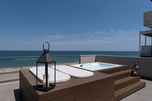 Terraza de madera con jacuzzi y una linterna, con vistas al mar.