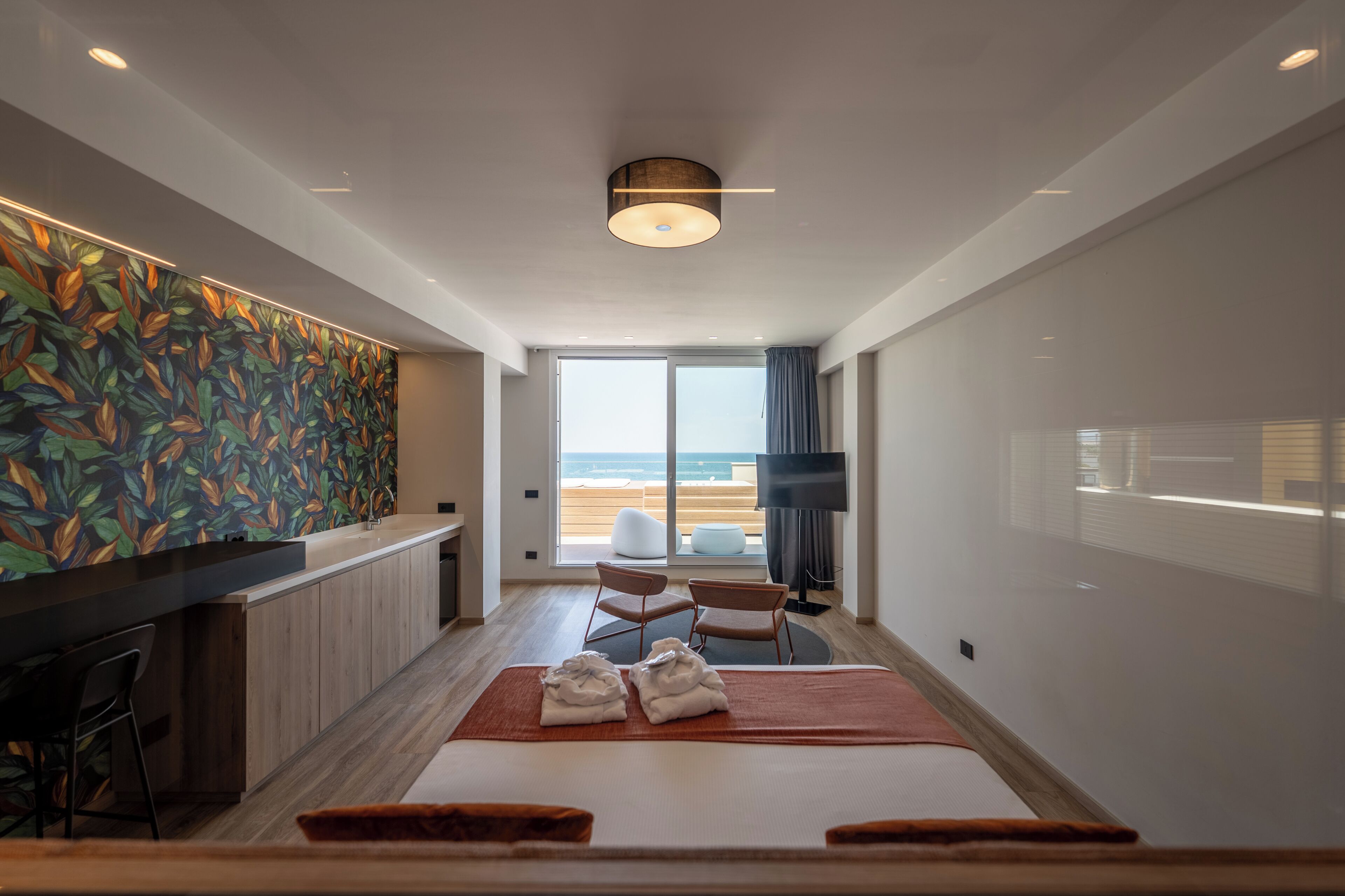 Un hotel moderno con una cama grande, un escritorio y vistas a la playa.
