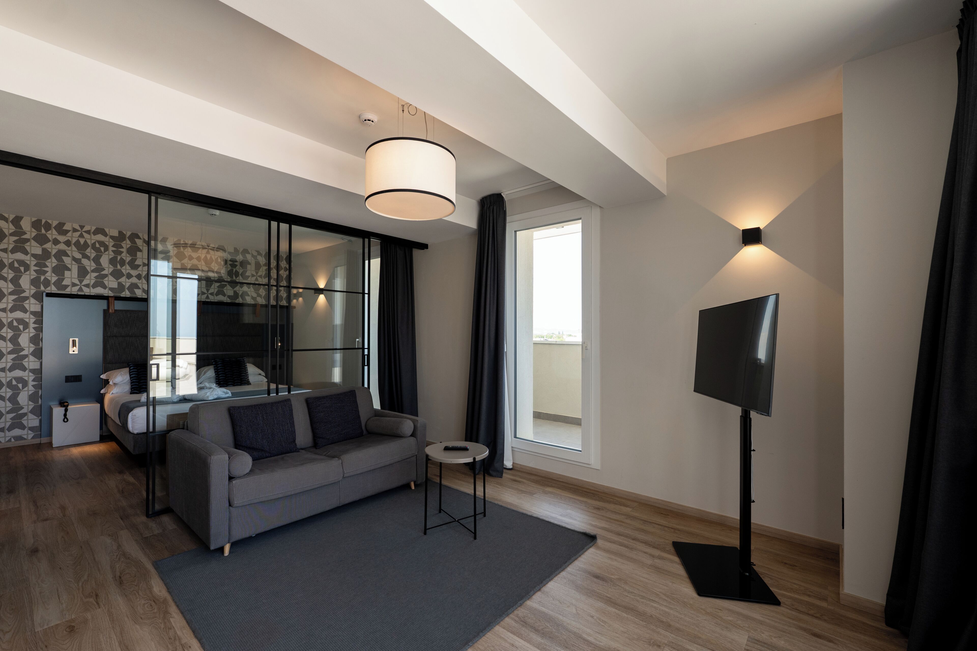 A modern living room with a sofa, a TV, a small table, and a large window.