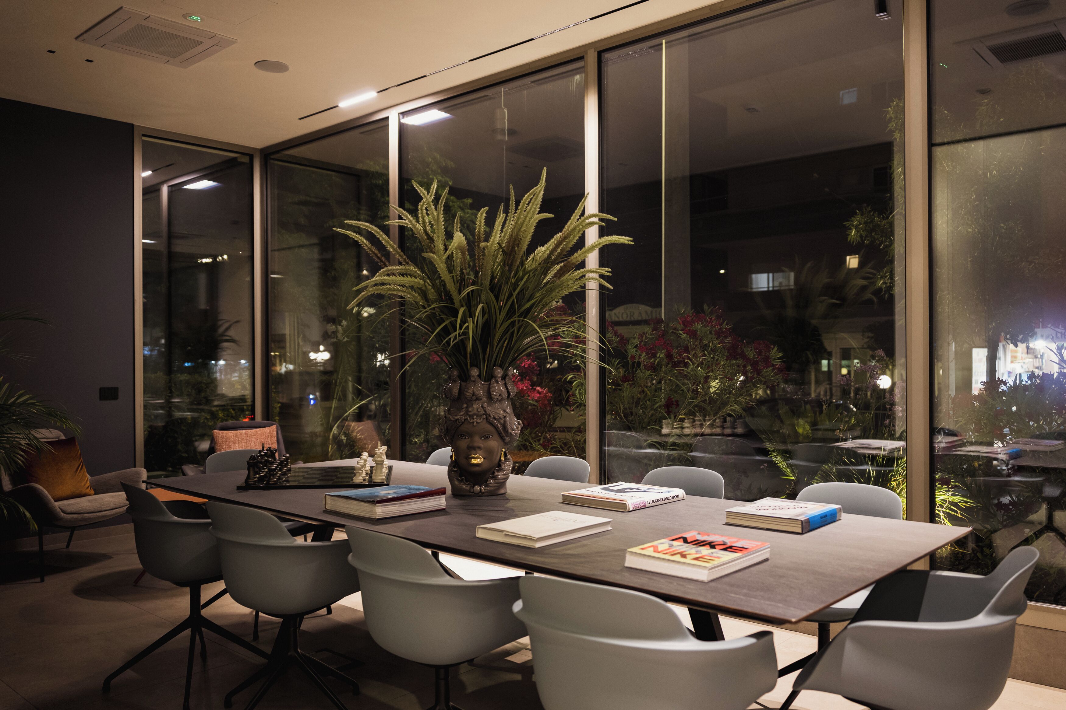 A conference room with a long table, chairs, and a large window with a view of the outdoors.