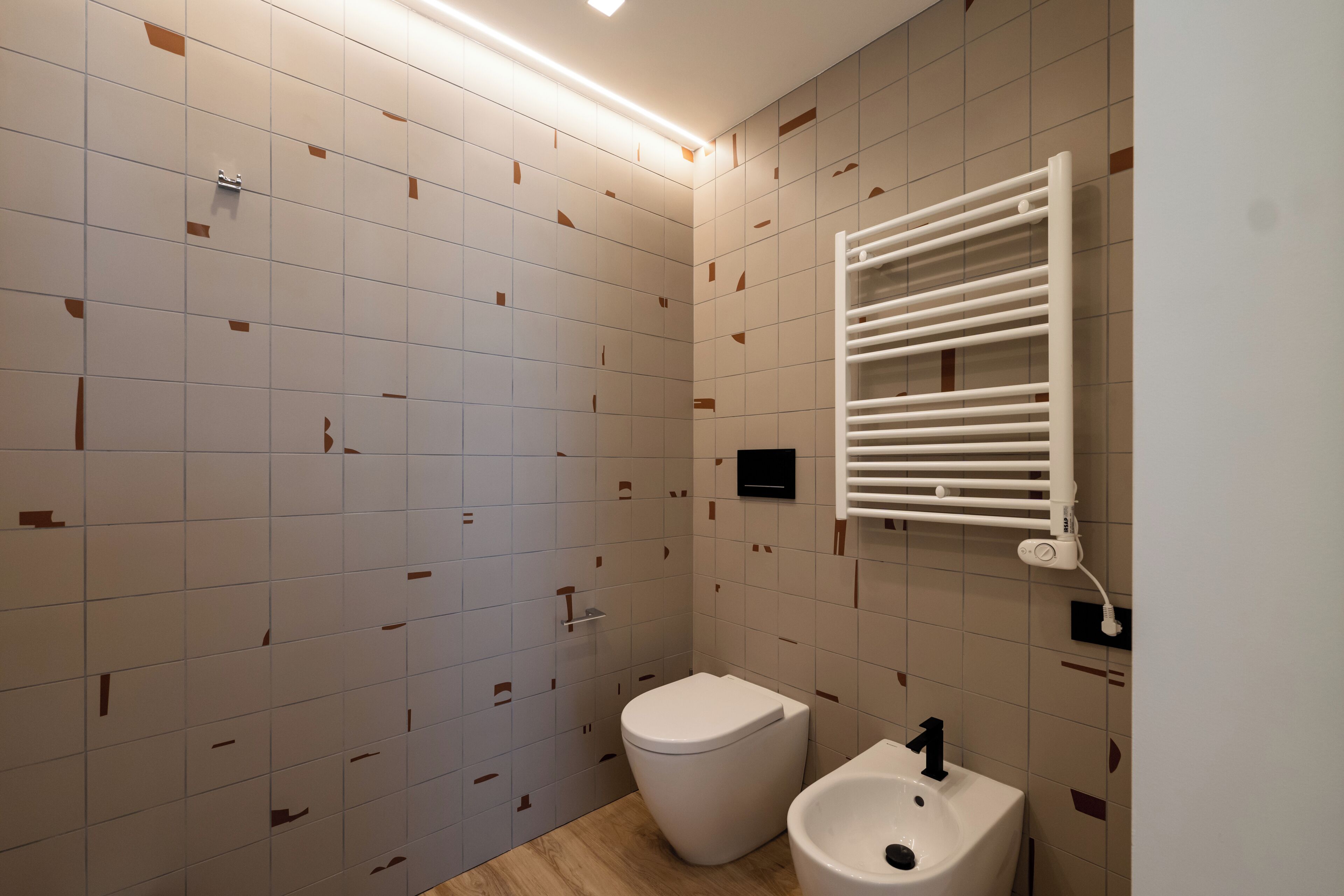 Un baño moderno con inodoro, bidé y un perchero para toallas.