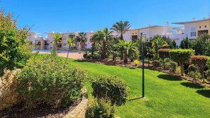 Ein modernes Hotel mit mehrstöckigen Gebäuden, einem gepflegten Garten mit verschiedenen Pflanzen und einem klaren, blauen Himmel.