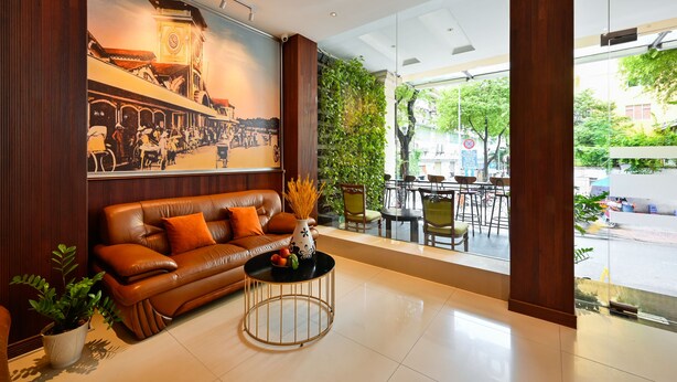 Un hall d’entrée moderne avec un canapé en cuir, une table basse ronde et une grande fresque représentant un paysage urbain.