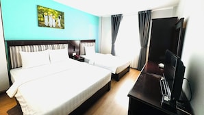 Une chambre d’hôtel avec un grand lit, un plus petit lit, un bureau avec un ordinateur et un tableau au mur.