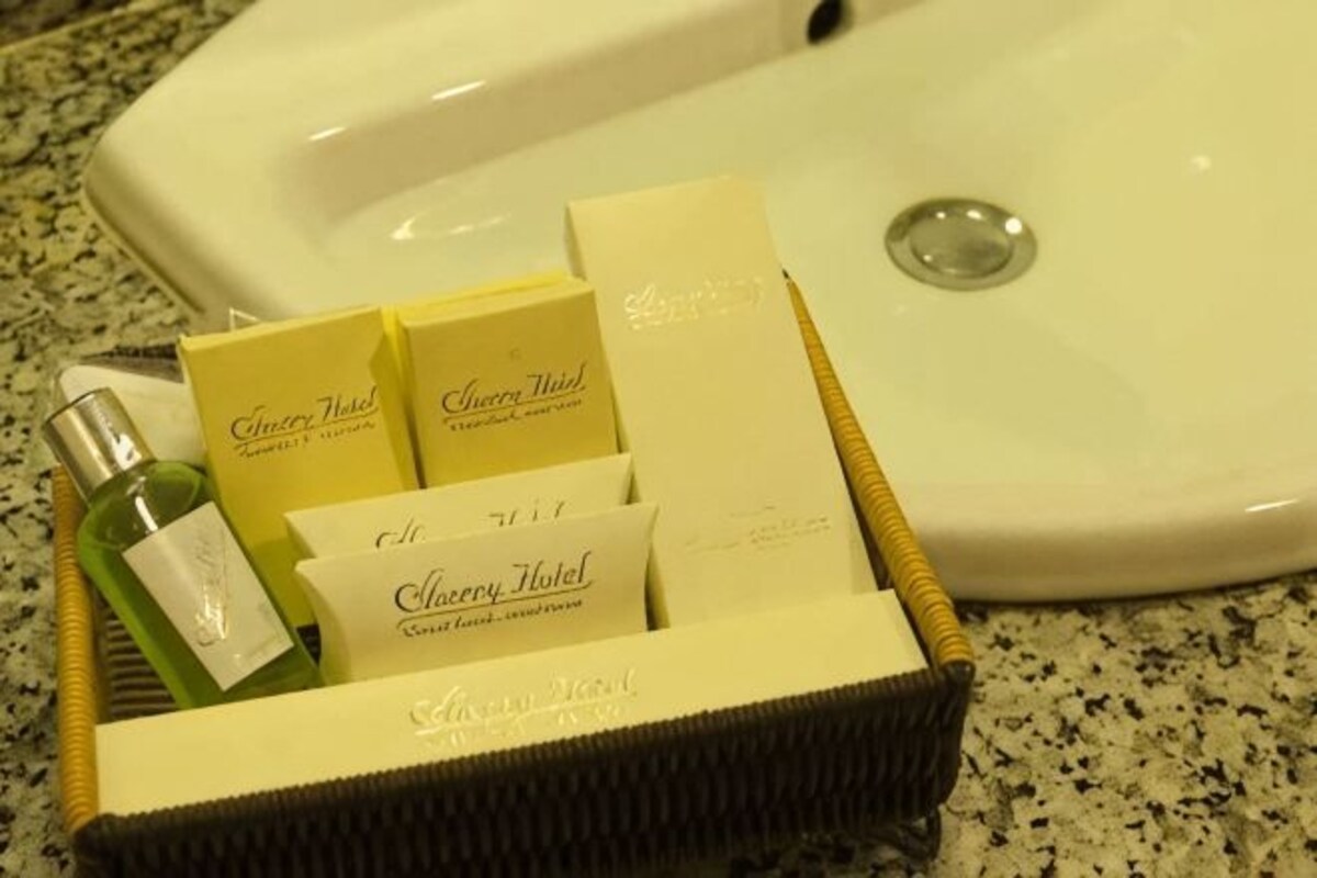 A wicker basket containing toiletries and a bottle of lotion, placed on a granite countertop near a sink.