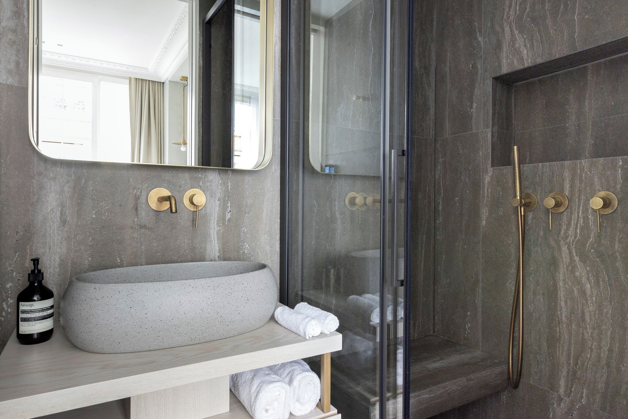 Un baño moderno con un lavamanos independiente, cabina de ducha con mampara de vidrio y un espejo grande.