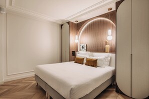 Une chambre à coucher moderne avec un grand lit, un lambris en bois sur les murs et un luminaire au plafond aux lignes courbes.