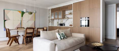 A modern living room with a sofa, coffee table, and dining area with chairs and a table.