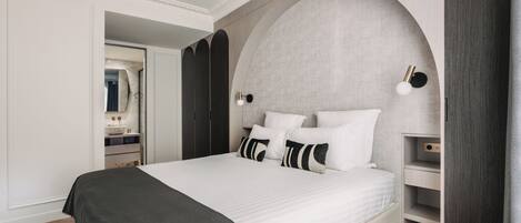 A modern bedroom with a large bed, a built-in wardrobe, and a curved wall design.
